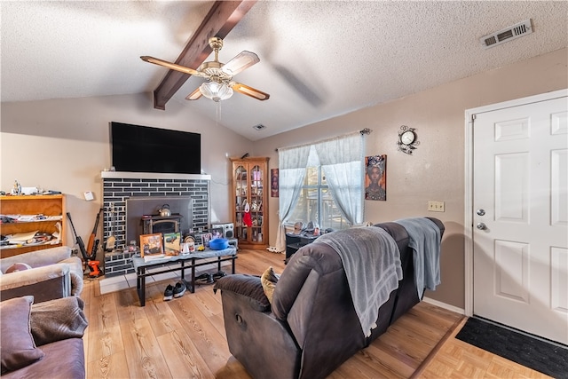 living room featuring ceiling fan, lofted ceiling with beams, a textured ceiling, and light wood-type flooring