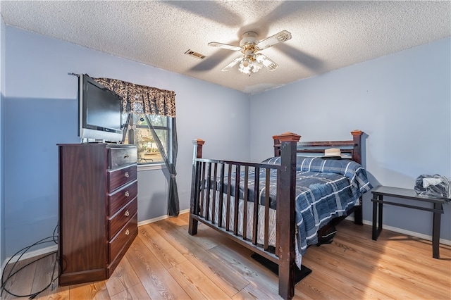 bedroom with a textured ceiling, light hardwood / wood-style floors, and ceiling fan