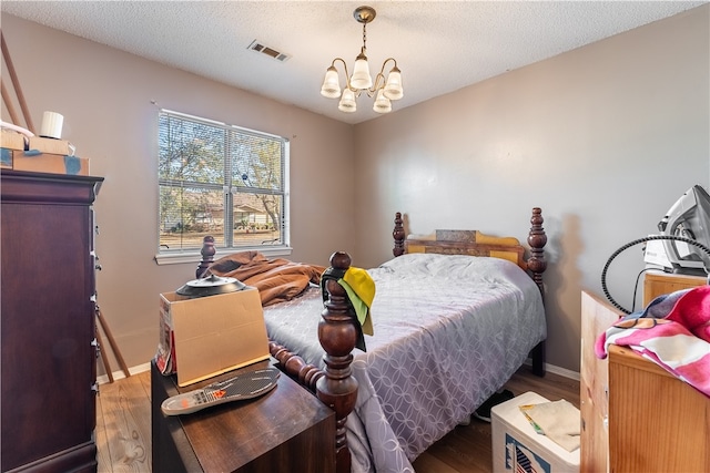 bedroom with a textured ceiling, a chandelier, and dark hardwood / wood-style floors