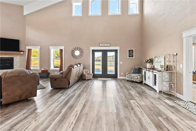 13136 Cedar Grove Rd, Lead Hill, AR 72644 - living area with french doors, a towering ceiling, a fireplace, wood finished floors, and baseboards