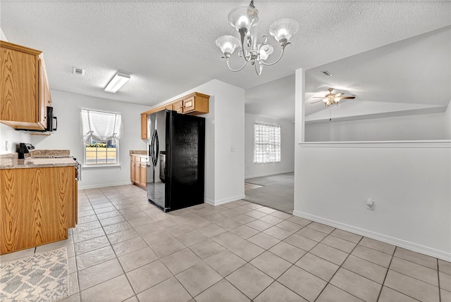 kitchen with light stone countertops, light tile patterned flooring, black appliances, ceiling fan with notable chandelier, and vaulted ceiling