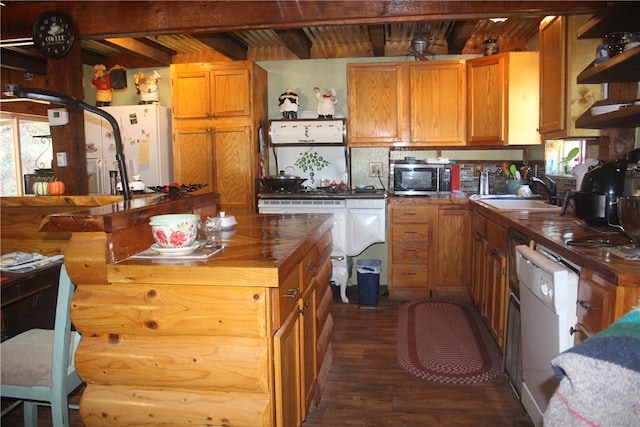 kitchen with beam ceiling, dark hardwood / wood-style flooring, butcher block counters, stainless steel appliances, and sink