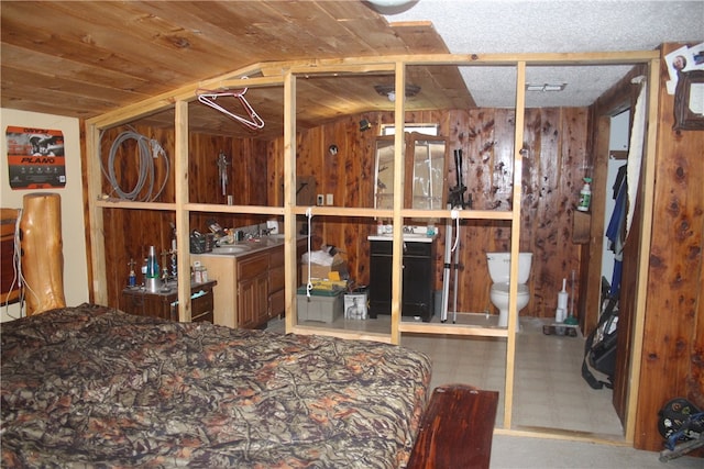 bedroom with lofted ceiling, wooden walls, sink, and wooden ceiling