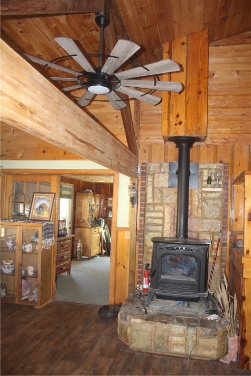 living room with wood walls, lofted ceiling, wood-type flooring, a wood stove, and ceiling fan