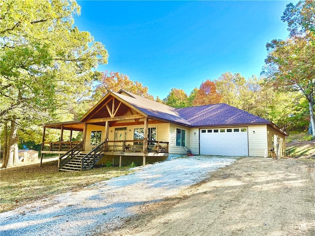 view of front facade featuring a porch, dirt driveway, and an attached garage