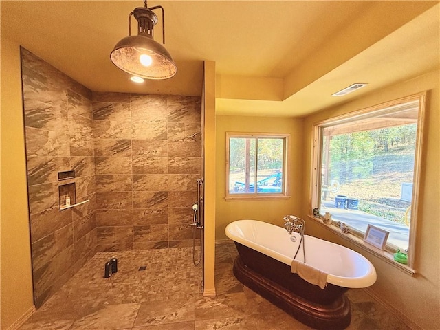 full bath featuring a stall shower, visible vents, a freestanding tub, and baseboards