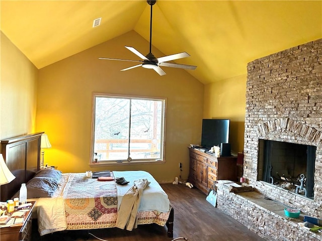bedroom with visible vents, a fireplace with raised hearth, baseboards, vaulted ceiling, and dark wood-type flooring