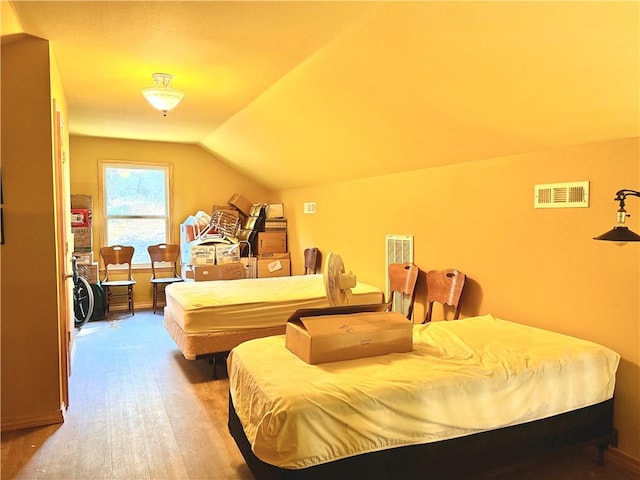 bedroom featuring visible vents, vaulted ceiling, and wood finished floors
