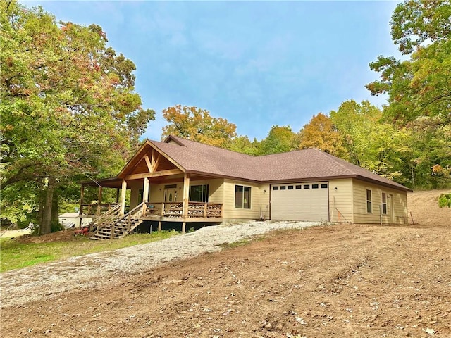 view of front facade featuring a porch, dirt driveway, and an attached garage