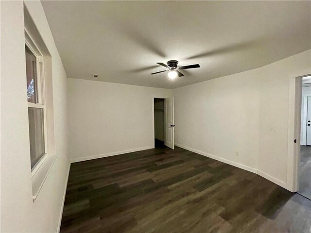 unfurnished room featuring dark wood finished floors, a ceiling fan, and baseboards