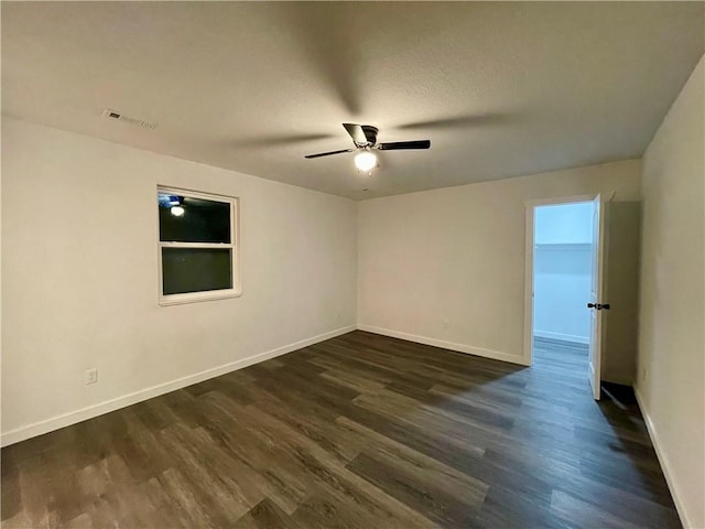 spare room with visible vents, baseboards, dark wood-type flooring, and a ceiling fan