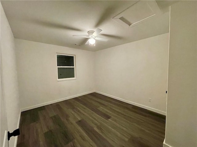 unfurnished room featuring baseboards, attic access, and dark wood finished floors