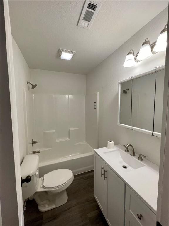 full bath featuring visible vents, toilet, vanity, wood finished floors, and a textured ceiling