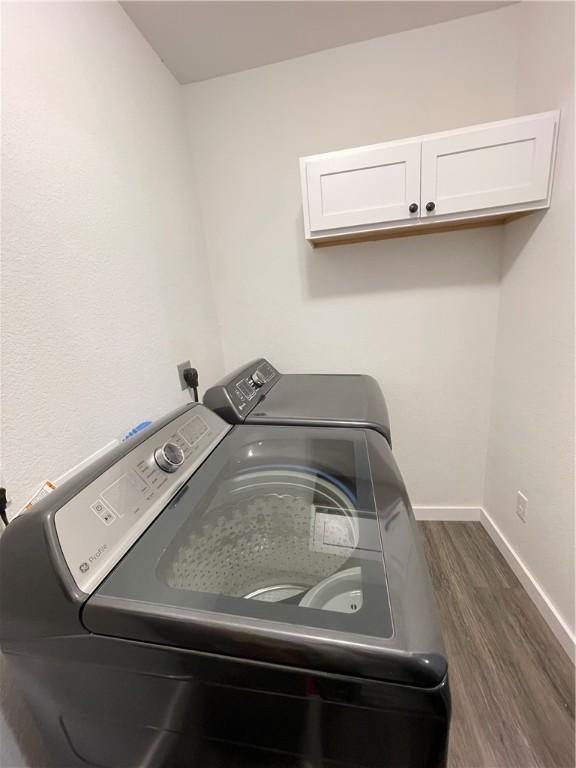 laundry room with cabinet space, washer and dryer, dark wood-type flooring, and baseboards