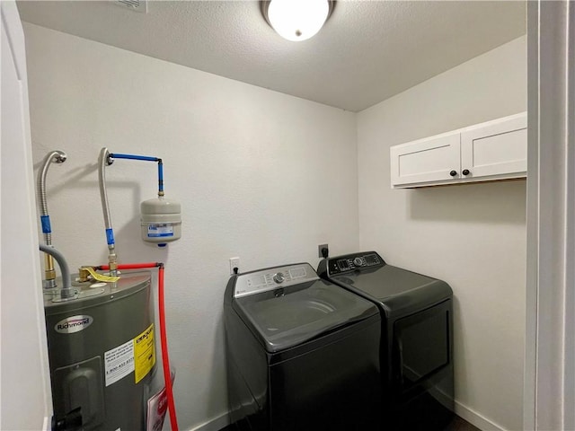 laundry area with a textured ceiling, water heater, cabinet space, baseboards, and washing machine and clothes dryer