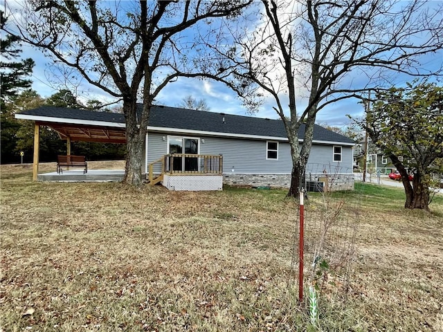 back of property with a yard, a wooden deck, and a patio area