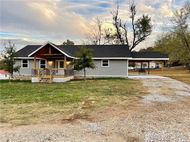 view of front of property featuring a front yard, driveway, roof with shingles, covered porch, and a carport