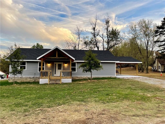 view of front facade featuring driveway, an attached carport, roof with shingles, covered porch, and a front yard