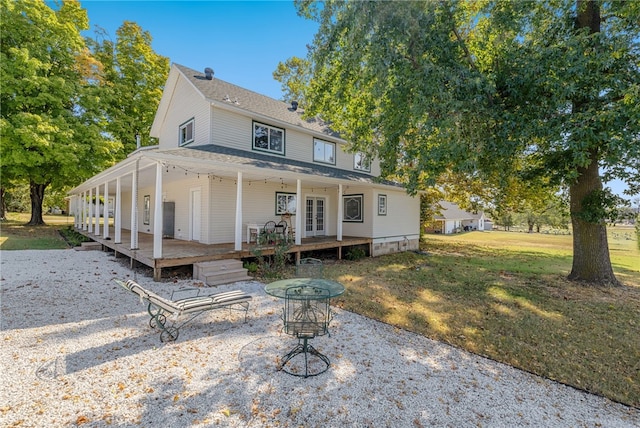 back of property with a wooden deck and a lawn