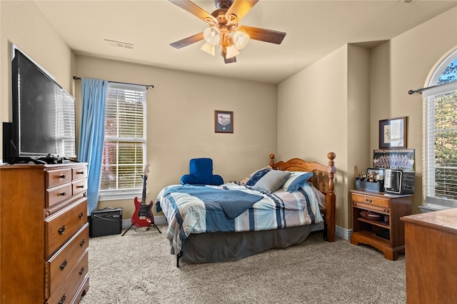 carpeted bedroom featuring multiple windows and ceiling fan