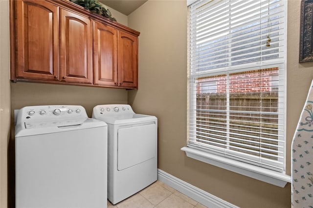 clothes washing area featuring washer and clothes dryer, cabinets, and light tile patterned floors