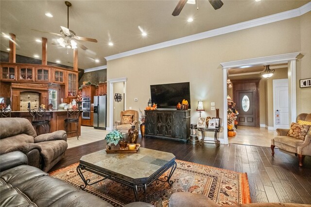 living room featuring a fireplace, hardwood / wood-style flooring, ceiling fan, and ornamental molding