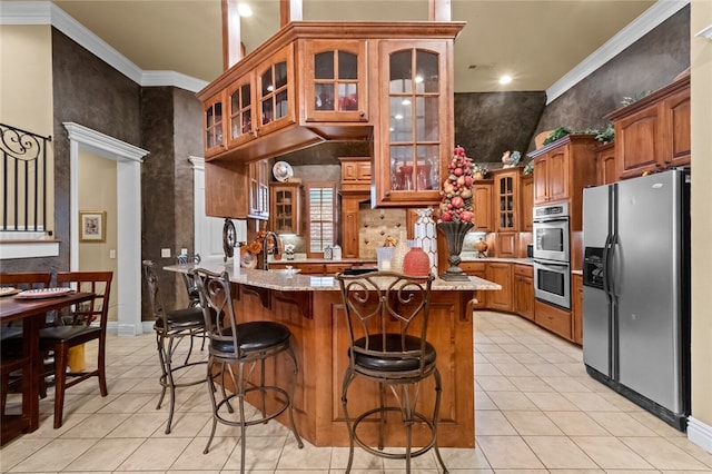 kitchen featuring ornamental molding, a kitchen bar, stainless steel appliances, and light stone counters