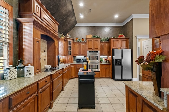 kitchen featuring light stone counters, crown molding, appliances with stainless steel finishes, light tile patterned floors, and lofted ceiling