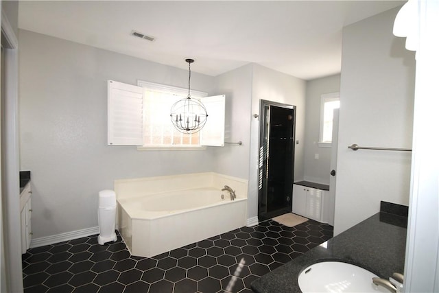 bathroom with tile patterned floors, a bathtub, vanity, and a chandelier