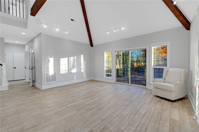 unfurnished living room with beam ceiling, track lighting, high vaulted ceiling, and light hardwood / wood-style floors