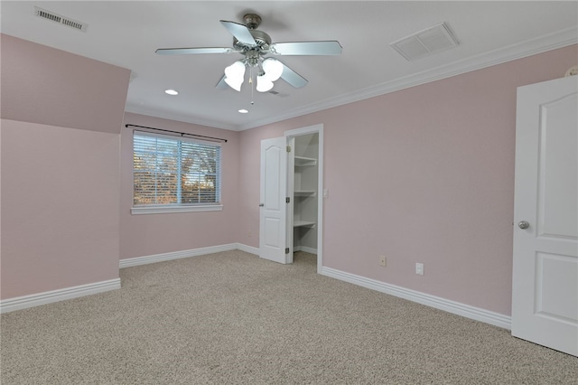 unfurnished bedroom featuring a spacious closet, ceiling fan, light colored carpet, and ornamental molding