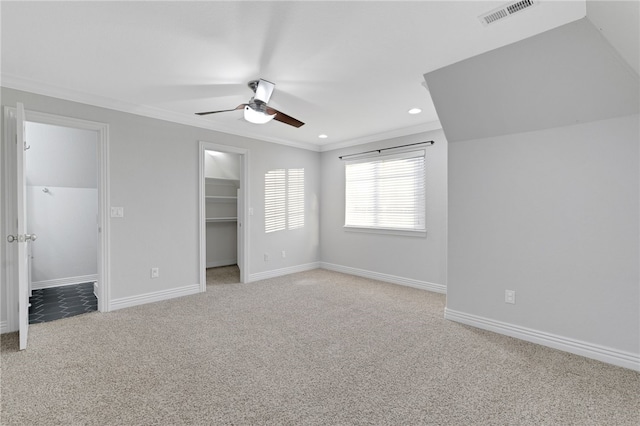 unfurnished bedroom featuring light carpet, ornamental molding, ceiling fan, a spacious closet, and a closet