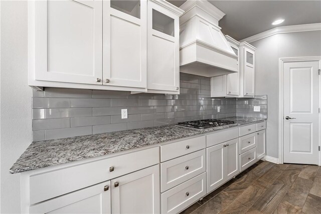 kitchen featuring premium range hood, backsplash, light stone countertops, white cabinets, and dark hardwood / wood-style flooring