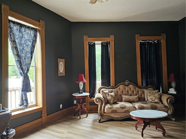 living area featuring ceiling fan, a textured ceiling, and light hardwood / wood-style flooring