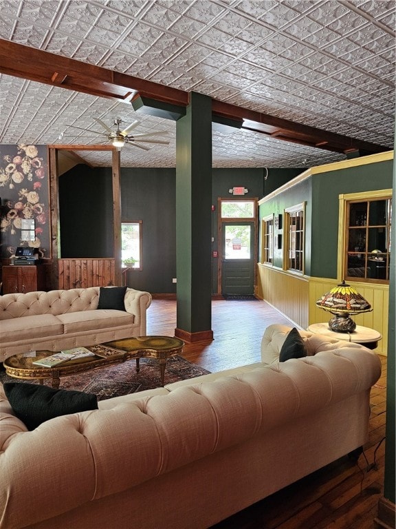 living room with beamed ceiling, wood-type flooring, plenty of natural light, and ceiling fan