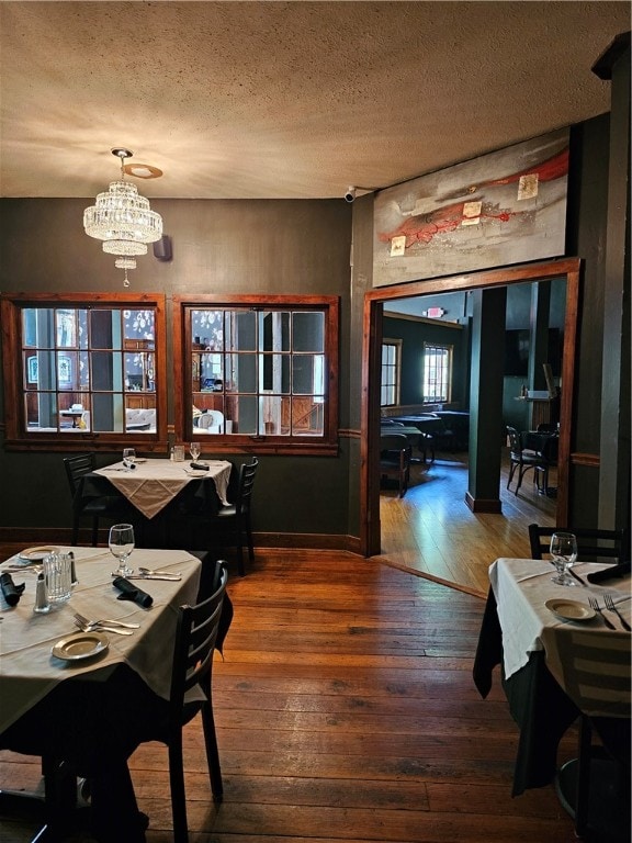 dining area featuring wood-type flooring, a textured ceiling, and a chandelier