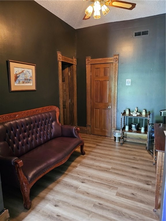 living area featuring light hardwood / wood-style floors, a textured ceiling, and ceiling fan