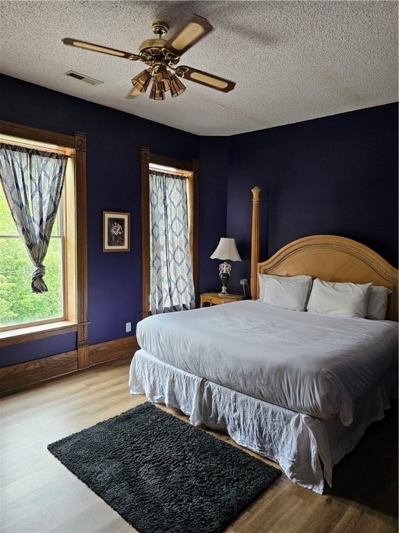 bedroom featuring ceiling fan, a textured ceiling, and hardwood / wood-style floors