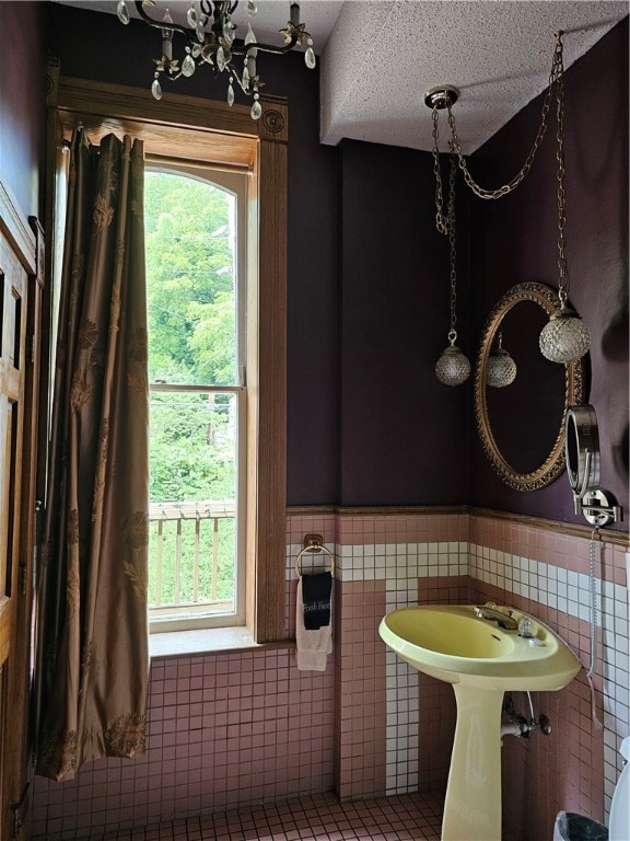 bathroom with a textured ceiling and tile walls