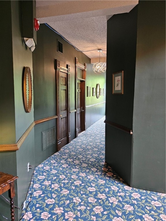 hall with a textured ceiling and an inviting chandelier