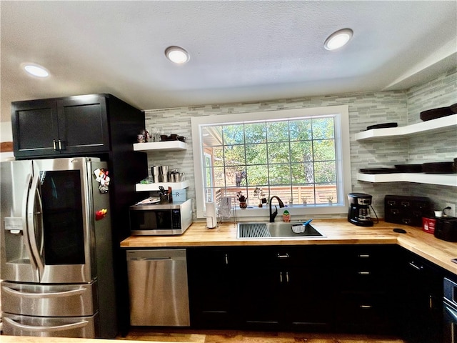 kitchen featuring tasteful backsplash, sink, butcher block counters, a textured ceiling, and stainless steel appliances