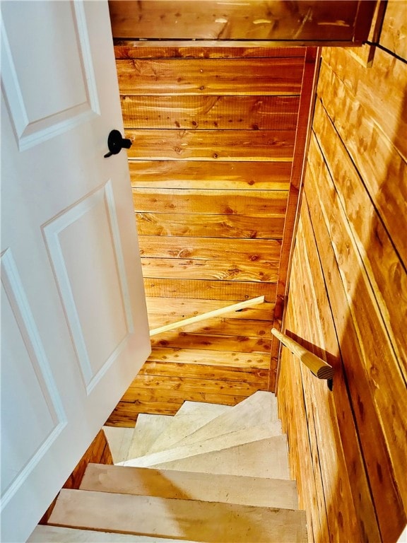 staircase with wood-type flooring and wood walls