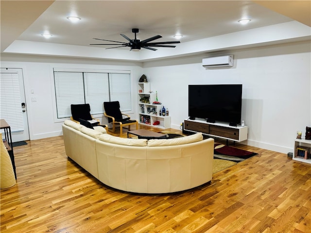 living room featuring an AC wall unit, light hardwood / wood-style floors, and ceiling fan