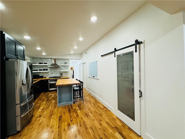 kitchen with a breakfast bar area, appliances with stainless steel finishes, a kitchen island, a barn door, and butcher block counters