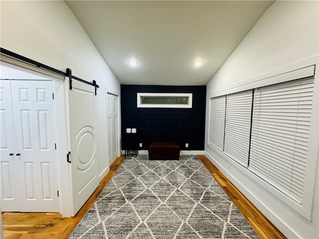 interior space with lofted ceiling, a barn door, and hardwood / wood-style floors