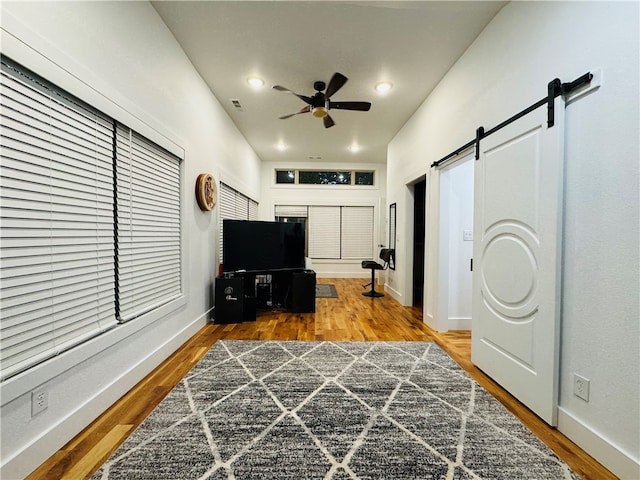 interior space with ceiling fan, a barn door, and hardwood / wood-style floors