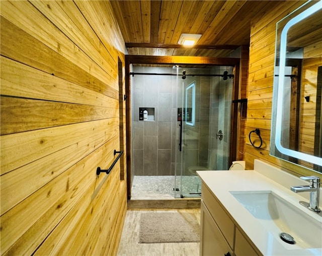 bathroom with hardwood / wood-style floors, vanity, an enclosed shower, and wood walls