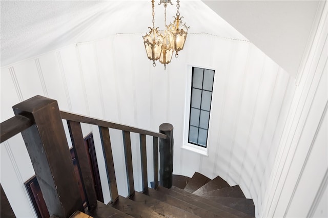 staircase with a notable chandelier