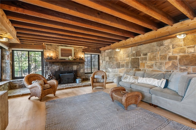 living room featuring beamed ceiling, light hardwood / wood-style floors, a wood stove, and wood ceiling