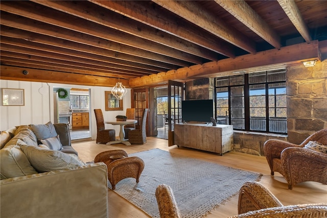 living room featuring beamed ceiling, an inviting chandelier, and light wood-type flooring